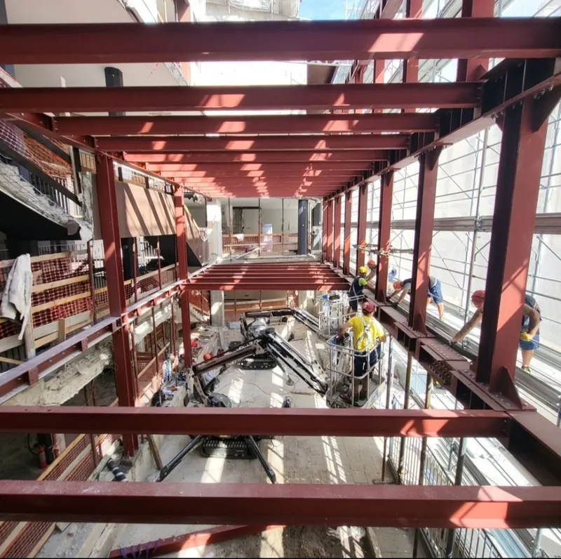 Montaje de la estructura metálica del hotel de Milán con operarios y plataforma elevadora