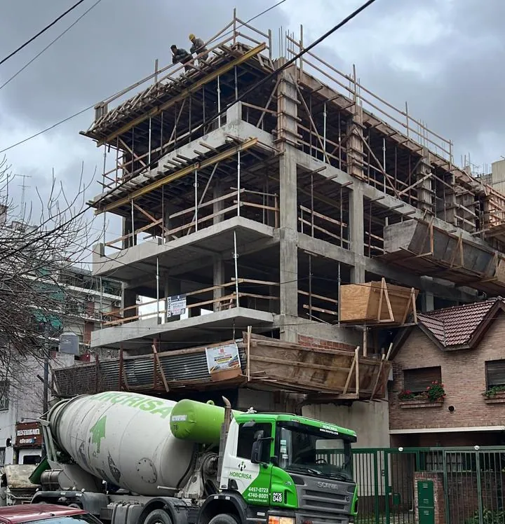 Estructura de hormigón armado en ejecución, con encofrados y un camión mixer en la calle
